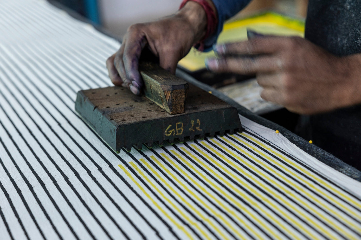 Person using a stamp on a textured surface with visible text 'GB 22'.