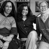 Three women sitting together in a room with decorative elements.